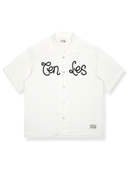 オレンジレッドの背景にレトロプリントが施されたキューバカラーの半袖シャツの正面ビュー。直線的でゆったりとしたカットが特徴で、リラックスしたカジュアルスタイルを提供します。