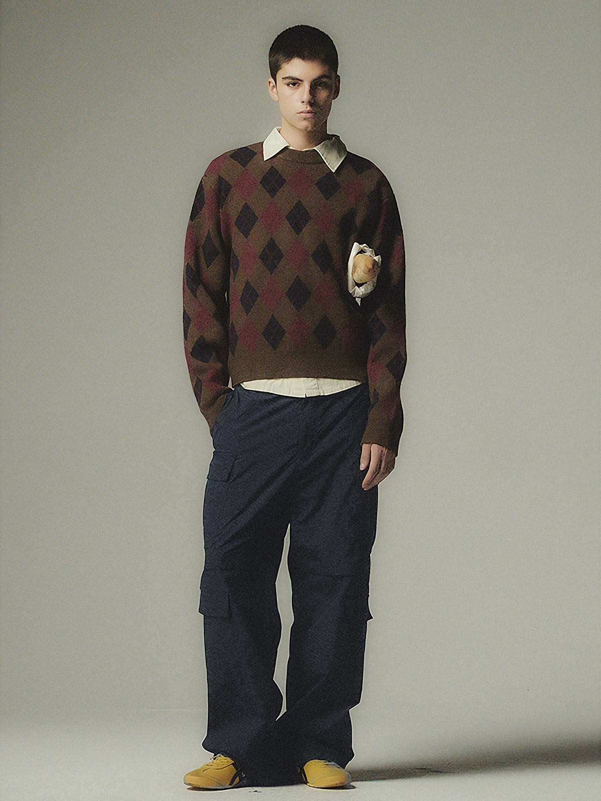 詳細画像: ダイヤ柄の滑らかな編み地のディテールクローズアップ画像。軽量で柔らかい混紡素材が持つ快適さと暖かさを示す。

モデル画像: ダイヤ柄クルーネックニットを着用したモデルによるカジュアルコーディネートイメージ。デニムやワークパンツとの組み合わせでレトロなスタイルを楽しめる。