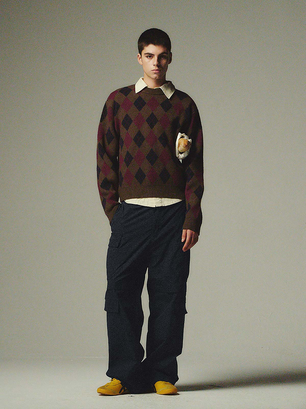 詳細画像: ダイヤ柄の滑らかな編み地のディテールクローズアップ画像。軽量で柔らかい混紡素材が持つ快適さと暖かさを示す。

モデル画像: ダイヤ柄クルーネックニットを着用したモデルによるカジュアルコーディネートイメージ。デニムやワークパンツとの組み合わせでレトロなスタイルを楽しめる。