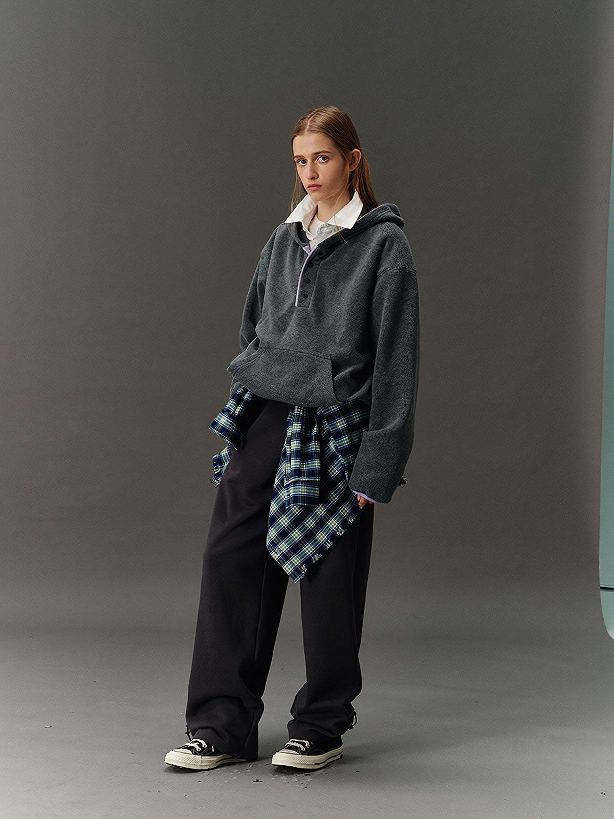 詳細画像: ハーフジップデザインと、シルエット調節可能な裾ドローコードのディテールクローズアップ画像。柔らかなフリース素材の質感が際立つ。

モデル画像: ハーフジップフリースフード付きスウェットを着用したモデルのコーディネート例。デニムやスウェットパンツと合わせたカジュアルでトレンド感あふれるスタイリングを表現。
