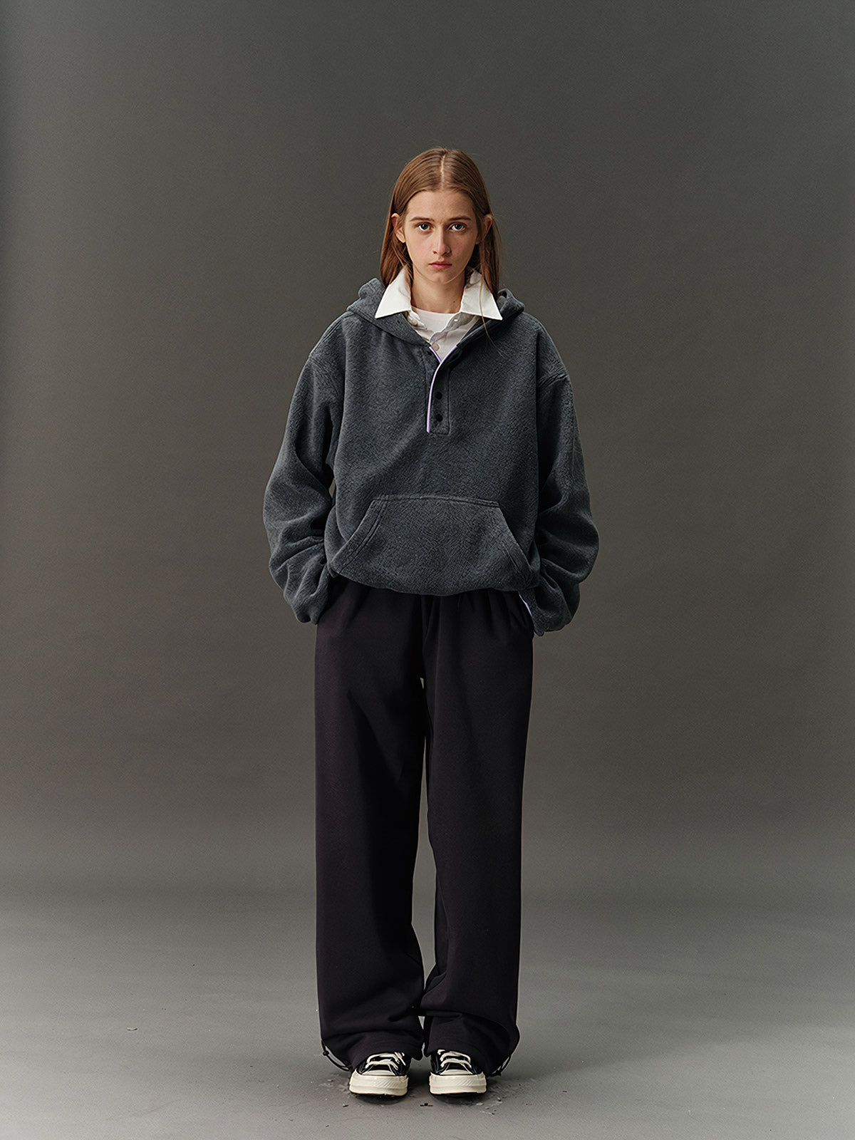 詳細画像: ハーフジップデザインと、シルエット調節可能な裾ドローコードのディテールクローズアップ画像。柔らかなフリース素材の質感が際立つ。

モデル画像: ハーフジップフリースフード付きスウェットを着用したモデルのコーディネート例。デニムやスウェットパンツと合わせたカジュアルでトレンド感あふれるスタイリングを表現。