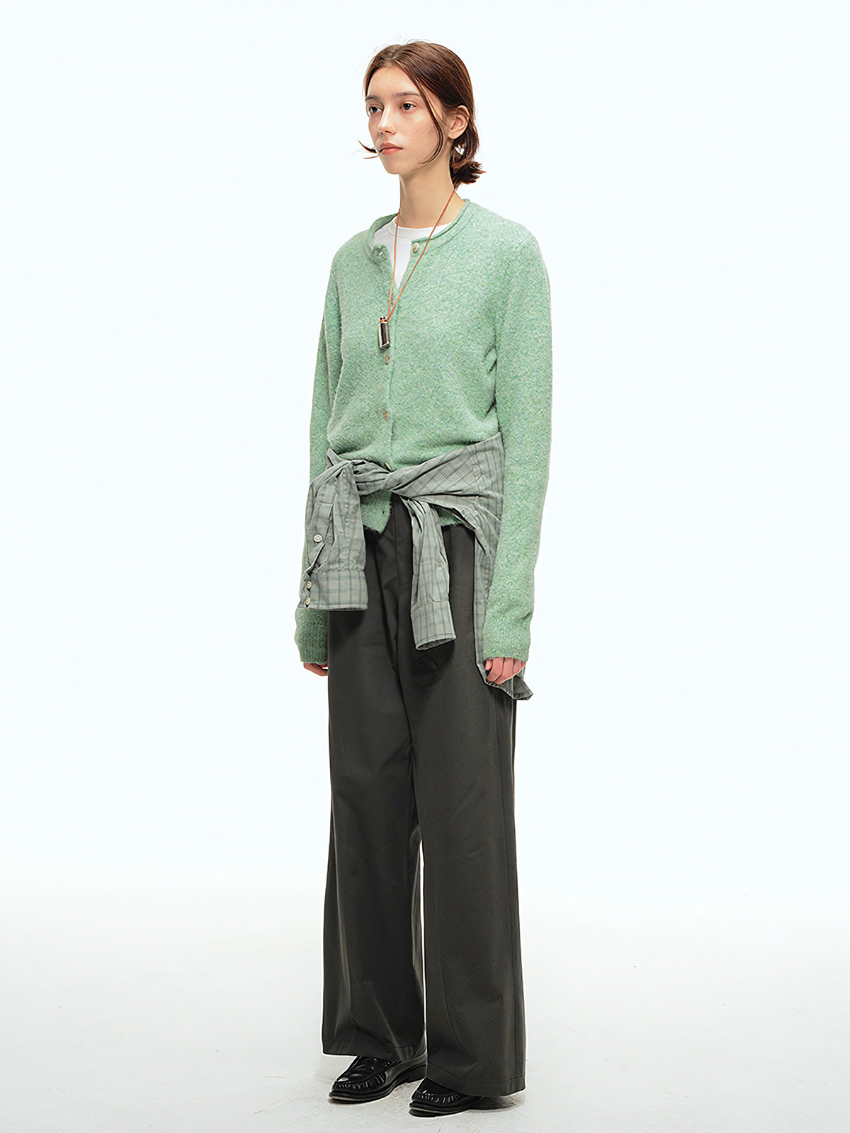 詳細画像: 前中プリーツデザインとハイウエストディテールのクローズアップ、優雅なドレープ感と流れるようなラインを強調
モデル画像: ワイドレッグスラックスをシンプルなシャツと合わせた通勤スタイル、ヴィンテージ感あふれるミニマルなコーディネート