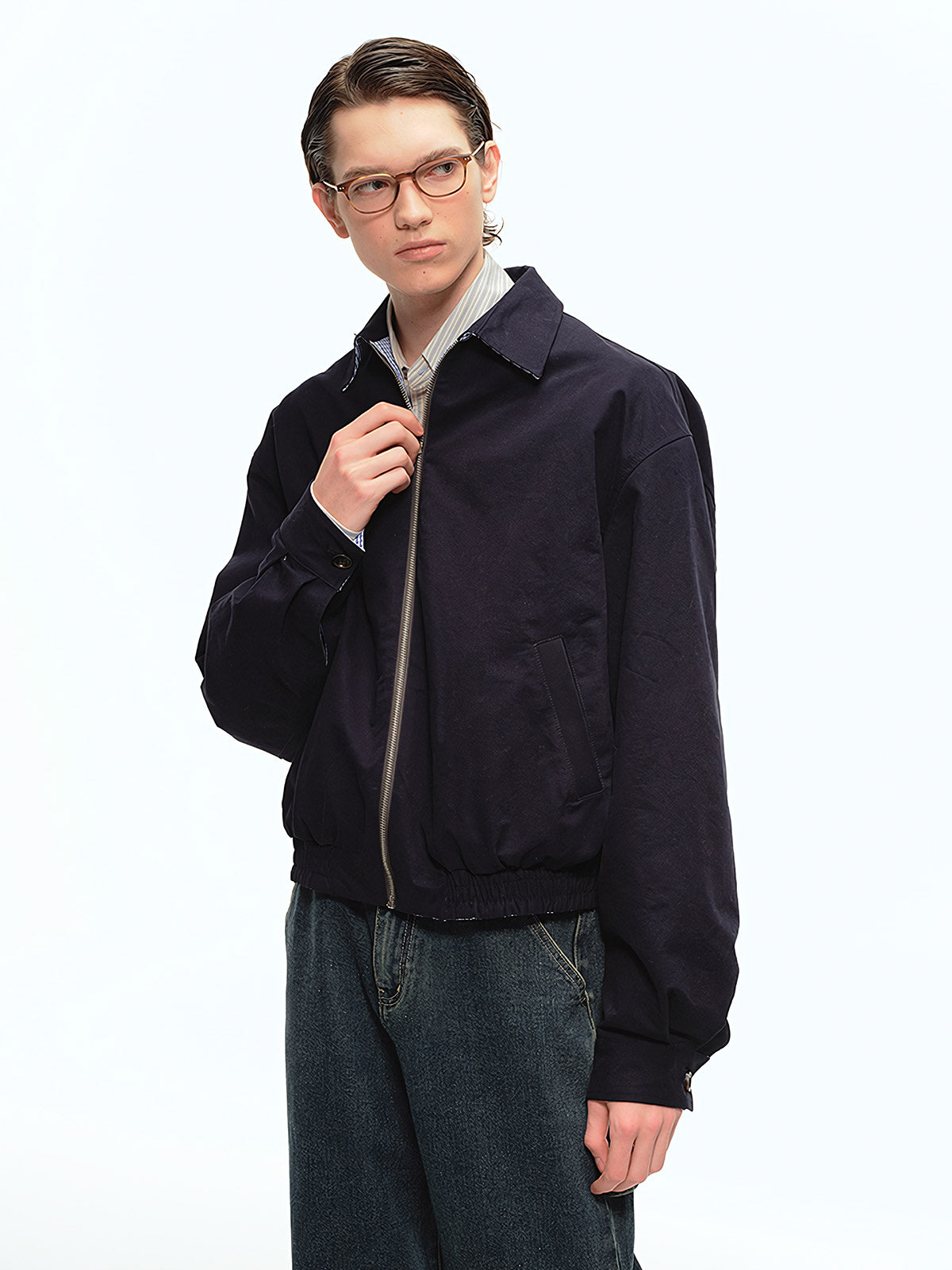 詳細画像: 袖口のバイカラー折り返しデザインとリバーシブルデザインのディテール、ヴィンテージチェック柄と単色面が交互に見える部分のクローズアップ
モデル画像: モデルがリバーシブルハリントンジャケットを使ったヴィンテージ感とモダンなコーディネート、カジュアルなスタイルを披露