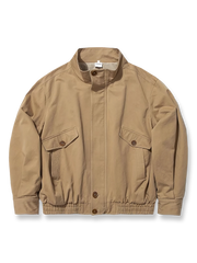 製品画像: ドレーピング（立体裁断）技法を活かしたスタンドカラーのワークジャケット全体展示、サンドウォッシュ加工とコーマコットン素材を使用したヴィンテージ感のあるデザイン

詳細画像: ドレーピングカットによる立体感、スタンドカラーのディテール、大容量ポケットのクローズアップ