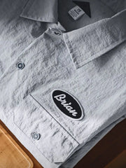 薄手のナイロン生地と2つの胸ポケットが特徴の半袖シャツ正面全体。肩のロゴ刺繍や控えめなスタイリングがわかる