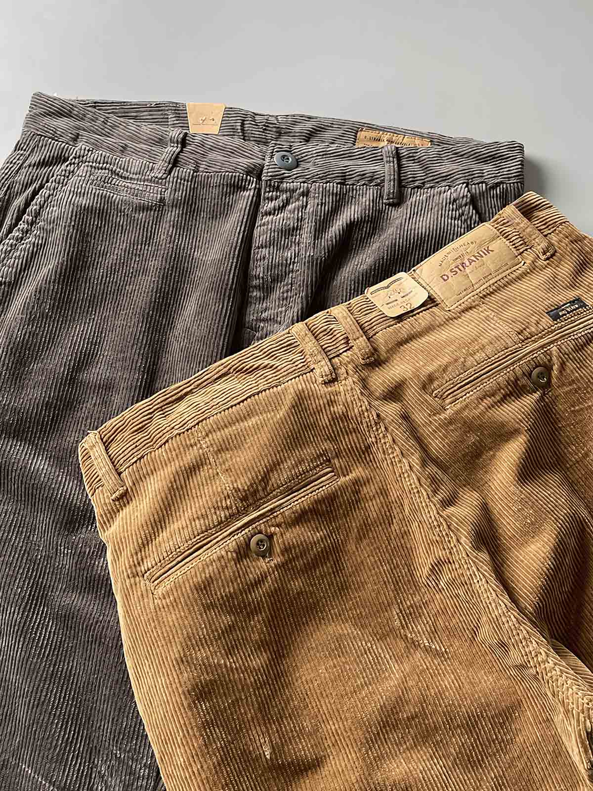 製品画像
高密度の14畝コーデュロイ素材を使用したストレートカーゴパンツ。クラシックなストレートシルエットとウォッシュ加工によるヴィンテージ感が特徴で、鉱山作業着の伝統を受け継ぐデザインが際立つ

詳細画像
バックポケットに施された二重補強ディテールとウエスト内側の丁寧なパイピング仕上げが、機能性とクラシックな仕立ての美学を象徴。コーデュロイの均一な畝立ちが繊細な質感を強調
