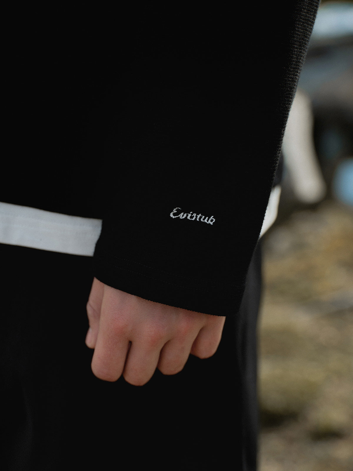 詳細画像: ワッフル生地のテクスチャーとレイヤードデザインの特写。独自の質感とディテールが着こなしに深みを加え、シンプルでありながらもデザイン性が光る。

モデル画像: ヘンリーネック長袖Tシャツを着用したカジュアルなレイヤードスタイルを披露するモデル。ゆったりとしたシルエットと快適さを兼ね備え、スタイリッシュな着こなしを実現。