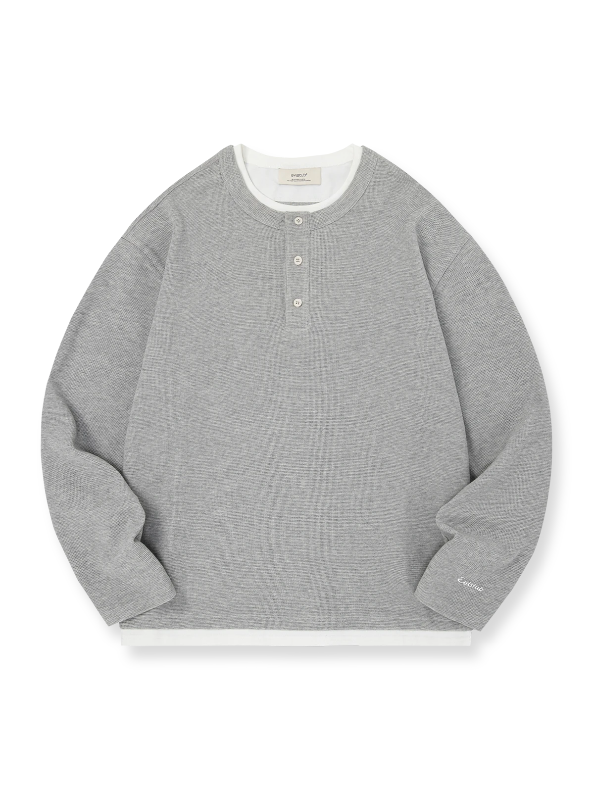 製品画像: ヘンリーネック レイヤード風 ワッフル 長袖Tシャツ全体展示。ヘンリーネックとレイヤード風デザインが融合したスタイル、ワッフル生地が独特の質感を引き立て、洗練されたカジュアル感を演出。

詳細画像: ワッフル生地のテクスチャーとレイヤードデザインの特写。独自の質感とディテールが着こなしに深みを加え、シンプルでありながらもデザイン性が光る。