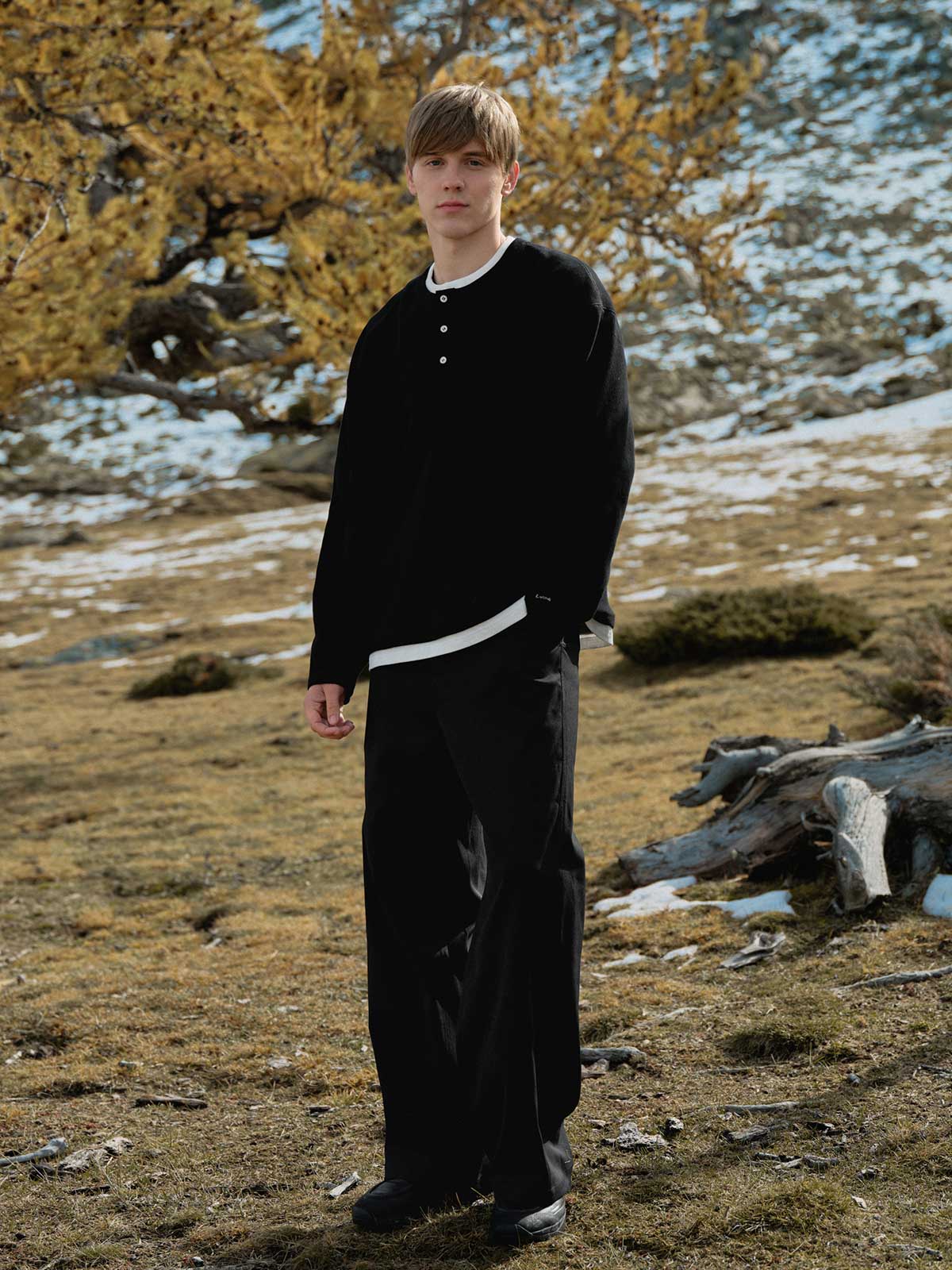 詳細画像: ワッフル生地のテクスチャーとレイヤードデザインの特写。独自の質感とディテールが着こなしに深みを加え、シンプルでありながらもデザイン性が光る。

モデル画像: ヘンリーネック長袖Tシャツを着用したカジュアルなレイヤードスタイルを披露するモデル。ゆったりとしたシルエットと快適さを兼ね備え、スタイリッシュな着こなしを実現。