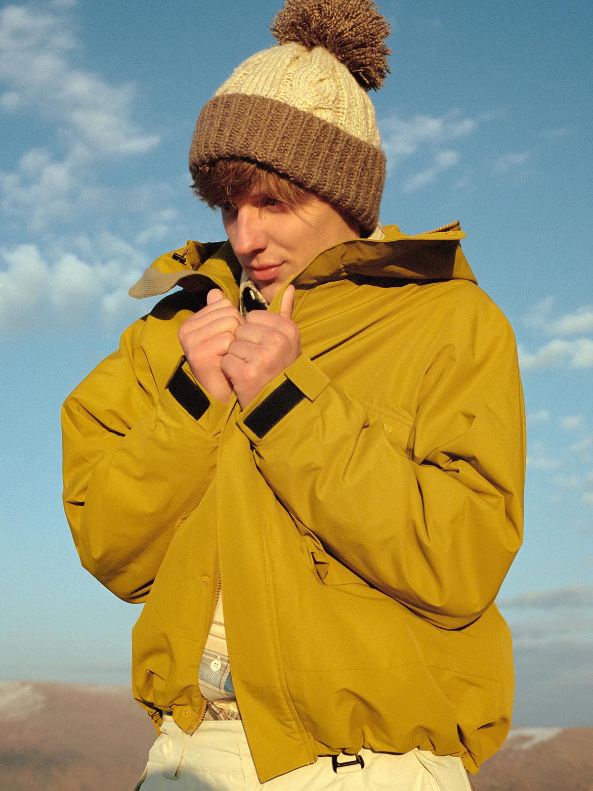 詳細画像: フロントの大きなポケットと背面ジップポケットのディテール展示 - 実用的な収納スペースが魅力。
モデル画像: モデル着用のアウトドアワークスタイルシェルジャケット - アウトドアや日常使いに活躍するスタイリング。