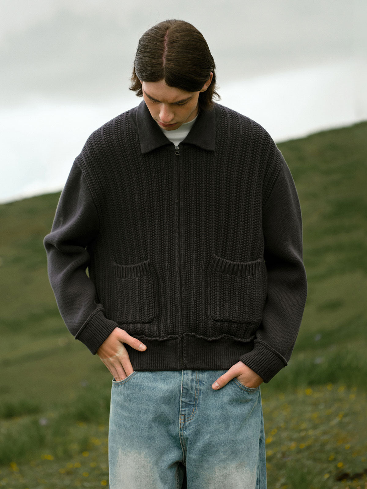 詳細画像: 太い編み目とケーブル模様のディテールを強調した展示。高品質な素材がもたらす柔軟さと安定性をアピール。
モデル画像: モデルが着用したレトロケーブル編みニットカーディガンの全体スタイリング。日常やアウトドアにぴったりなルーズフィットデザインを強調。