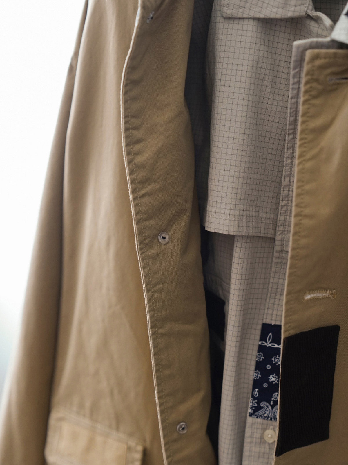 製品画像
クラシック バルマカーンコートの正面デザイン。Aラインシルエットと同系色のパッチワークデザインが際立ち、ブリティッシュスタイルの優雅さを表現

詳細画像
ヴィンテージ牛骨ボタンとフラップ付き暗ポケットのディテール特写。パッチワークデザインの不規則な切り替えラインが工芸美を際立たせ、耐久性と実用性が融合した細部の仕上がり