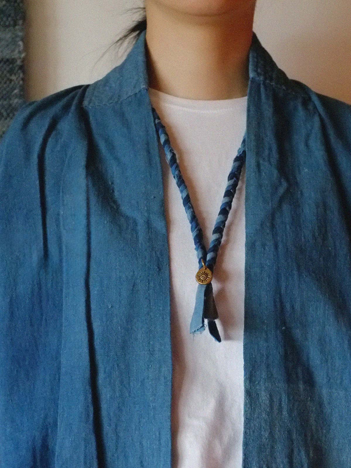 モデルが手作り編み込み飛鳥コインネックレスを着用し、シンプルな服装に洗練されたアクセントを加えている。