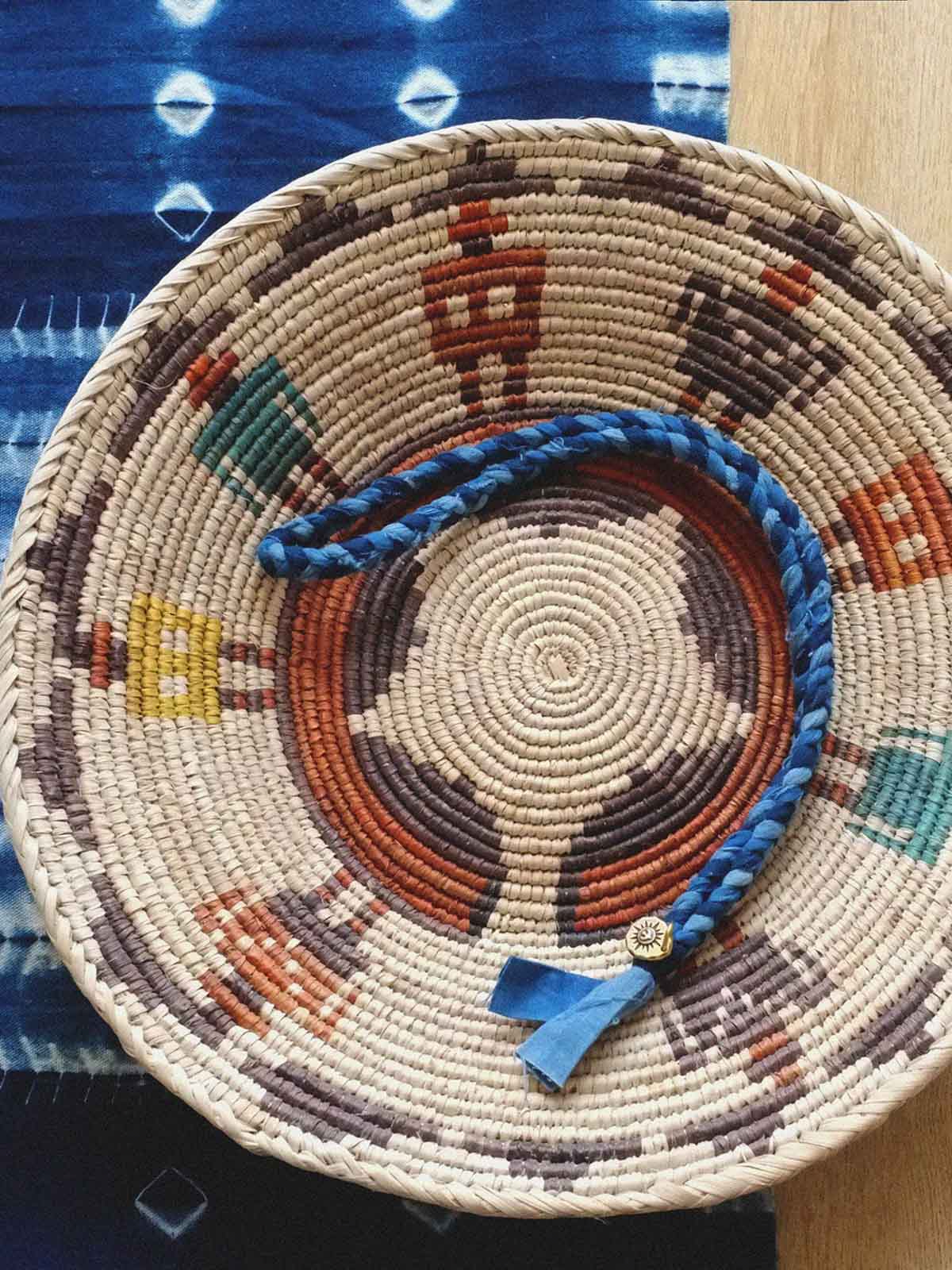 繊細な手作り編み込みと藍染めの詳細が際立つ飛鳥コインネックレスのクローズアップ。