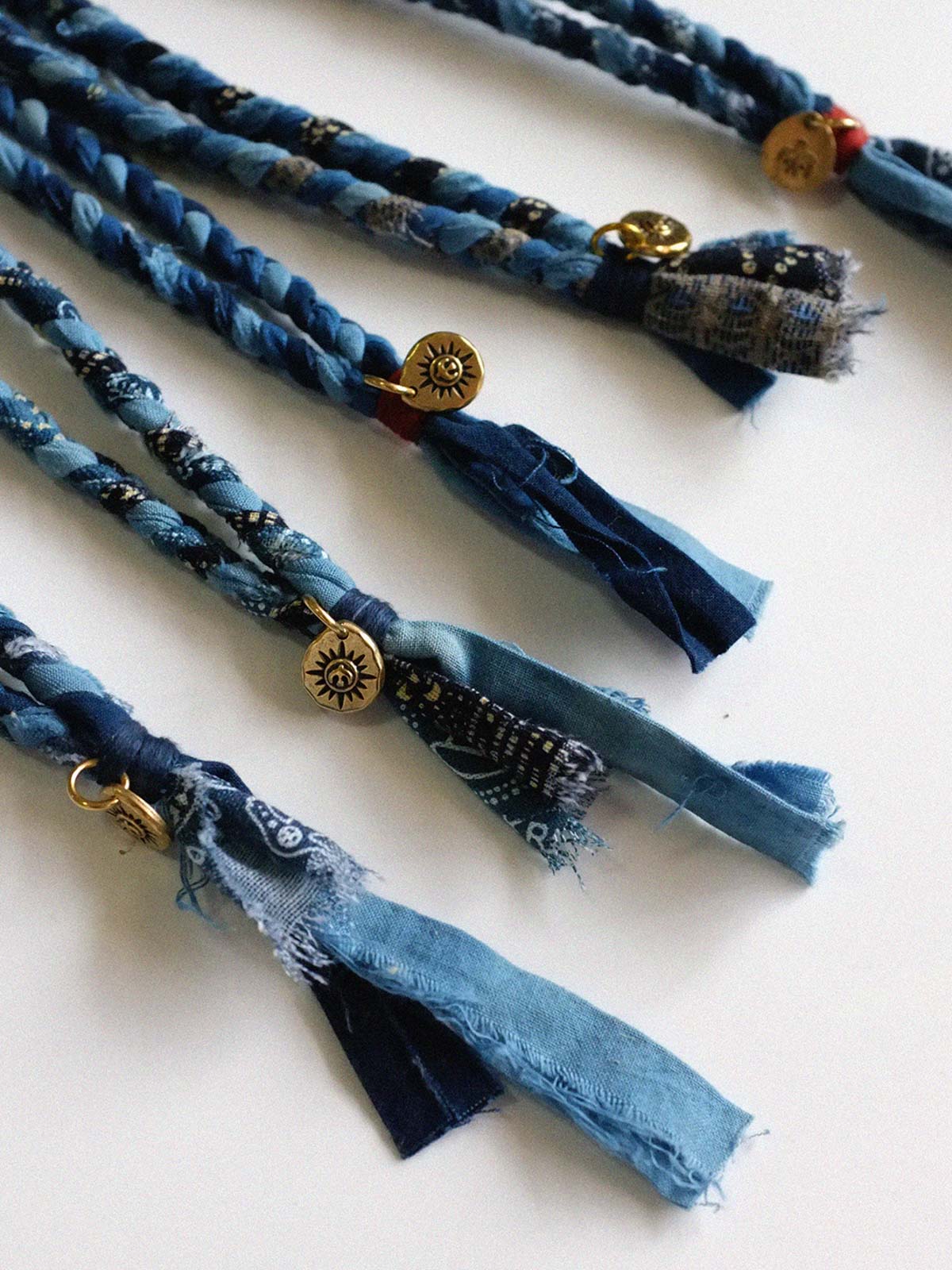 繊細な手作り編み込みと藍染めの詳細が際立つ飛鳥コインネックレスのクローズアップ。