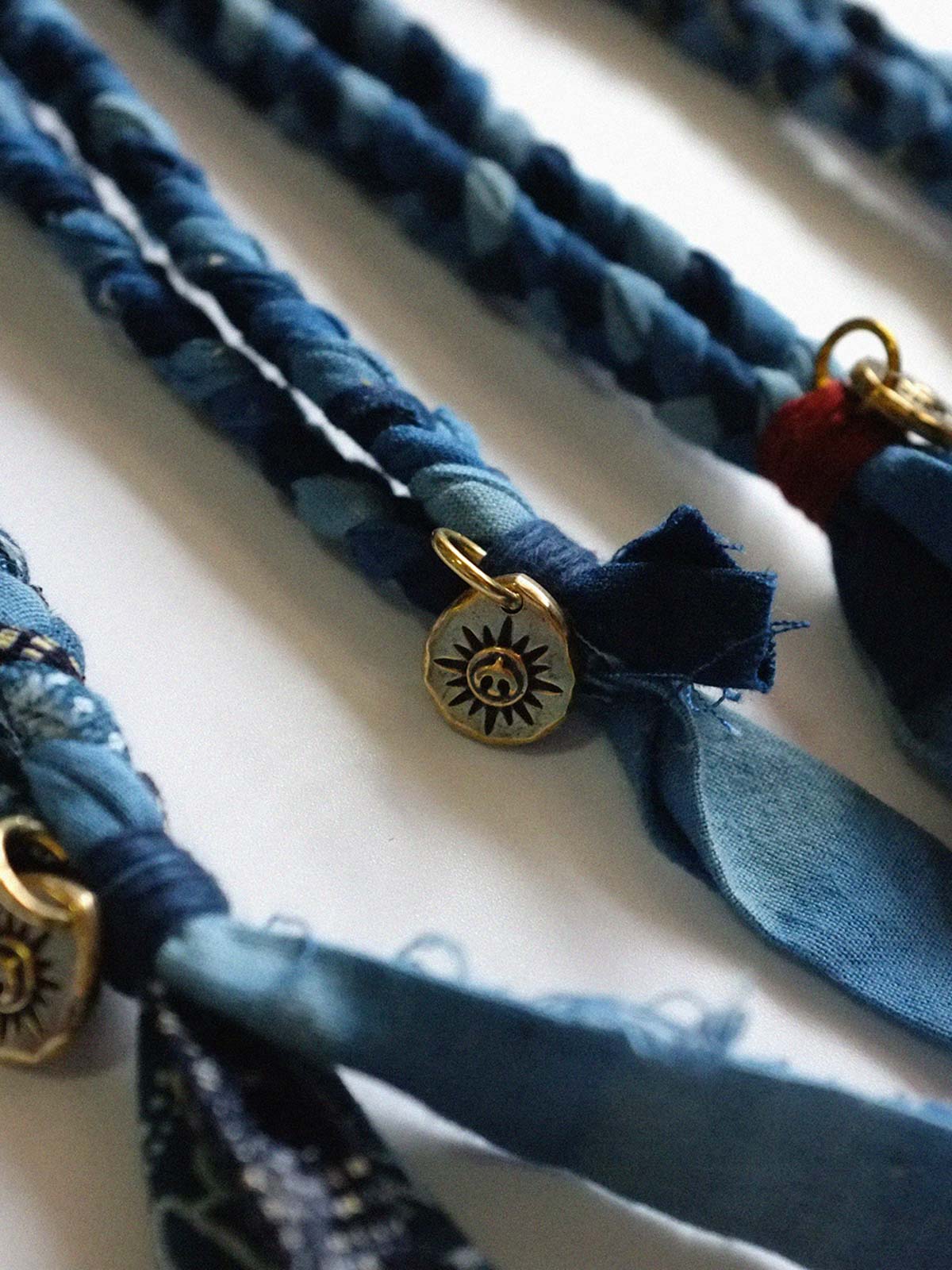 繊細な手作り編み込みと藍染めの詳細が際立つ飛鳥コインネックレスのクローズアップ。