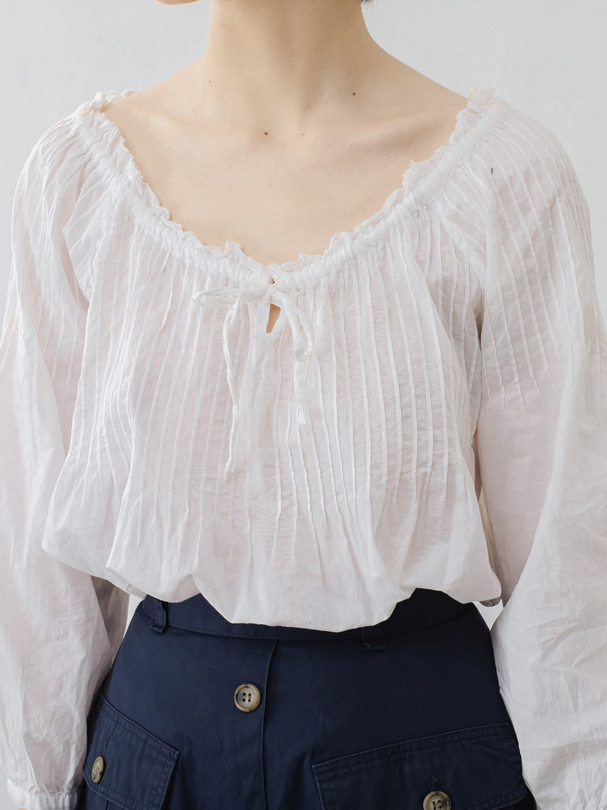 プリーツのディテールと調整可能なネックラインのクローズアップ