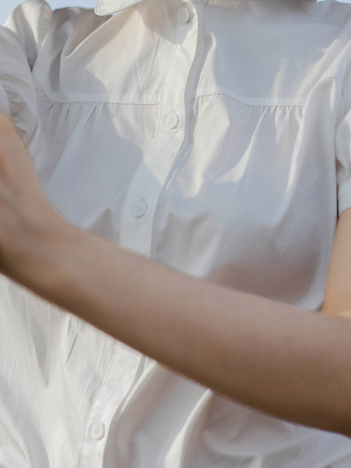 モデルが白色ピーターパンカラーシャツを着用し、シックなスタイルを披露