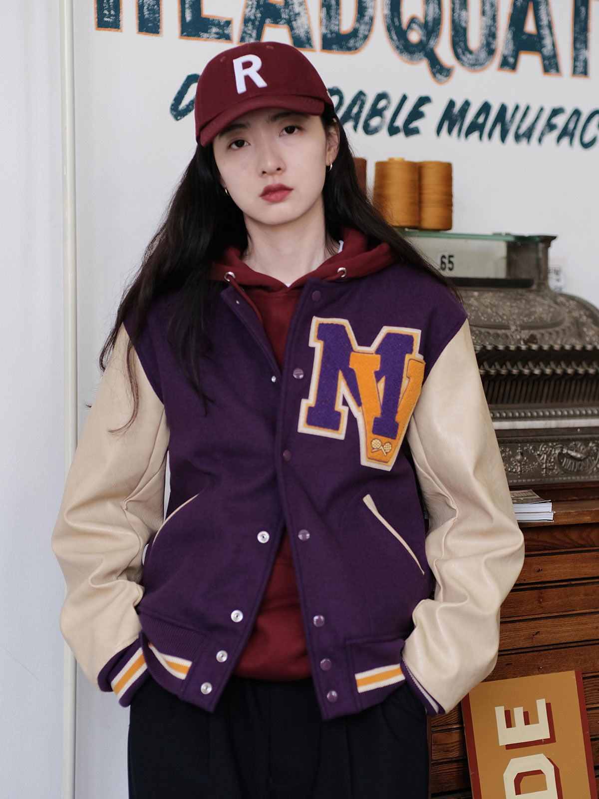 詳細画像: 刺繍レタリングとレザー切り替え袖のディテール、ヴィンテージ感のある精緻な作り
モデル画像: アイビー風ヴィンテージベースボールジャケットの着用イメージ、キャンパススタイルとストリートファッションの融合