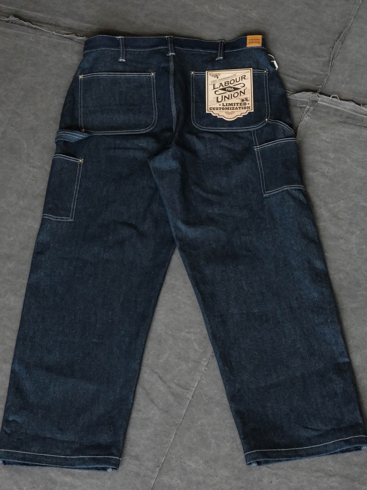 製品画像: ヴィンテージ感が漂う赤耳ナローフィットワークデニムパンツの正面画像。ルーズフィットのクラシックデザインが特徴
詳細画像: 14ozセルビッジデニムとリベットステッチのディテールが強調された画像