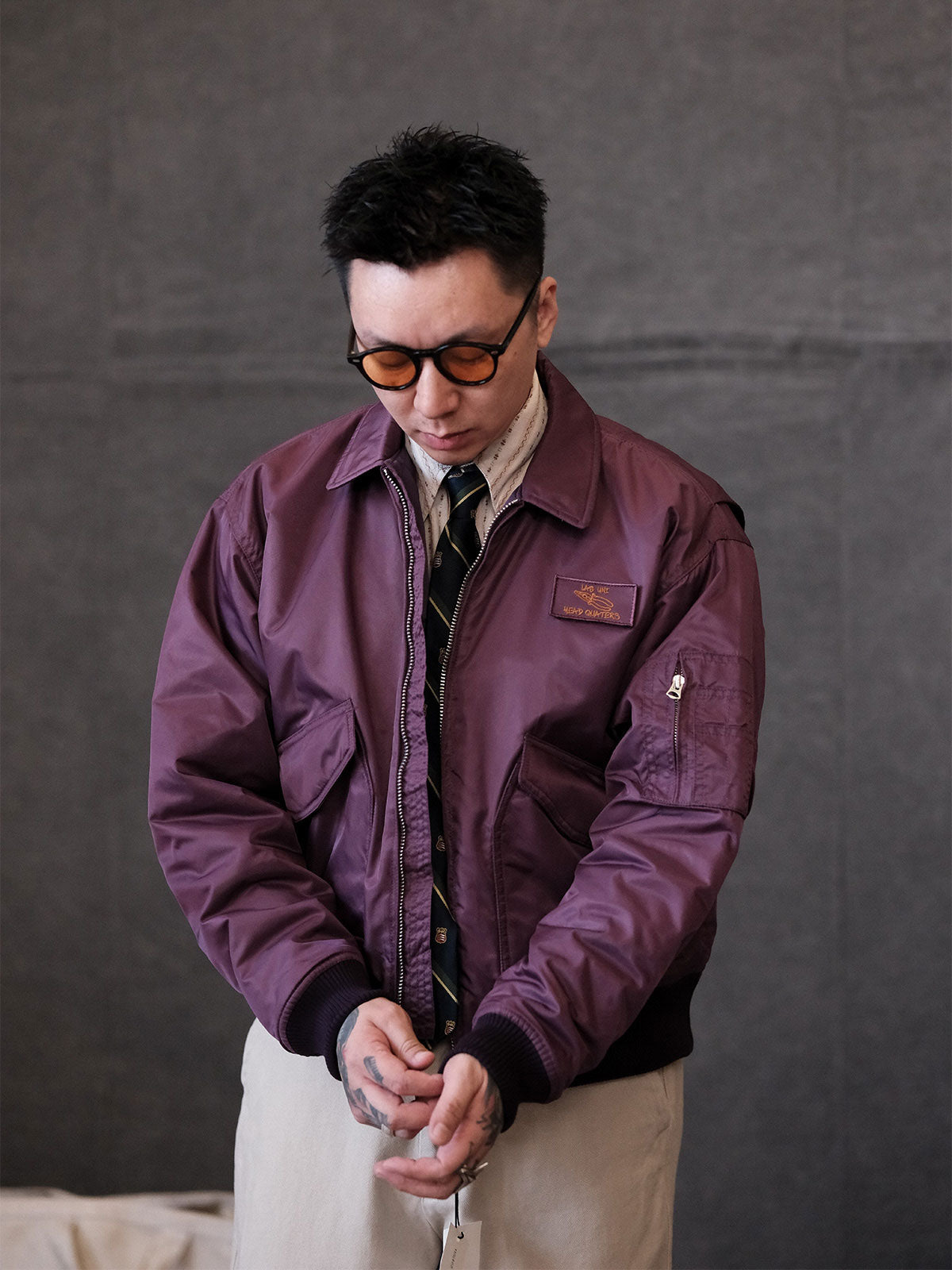 詳細画像:
TALONメタルジッパーとマジックテープエンブレムのディテール。フラップポケットやリブ編みの袖口、裾など、ミリタリーウェア特有のデザインが強調された画像。
モデル画像:
モデルがCWU-45Pフライトジャケットを着用し、ジーンズやカーゴパンツと組み合わせて、クラシックなミリタリースタイルを披露している画像。