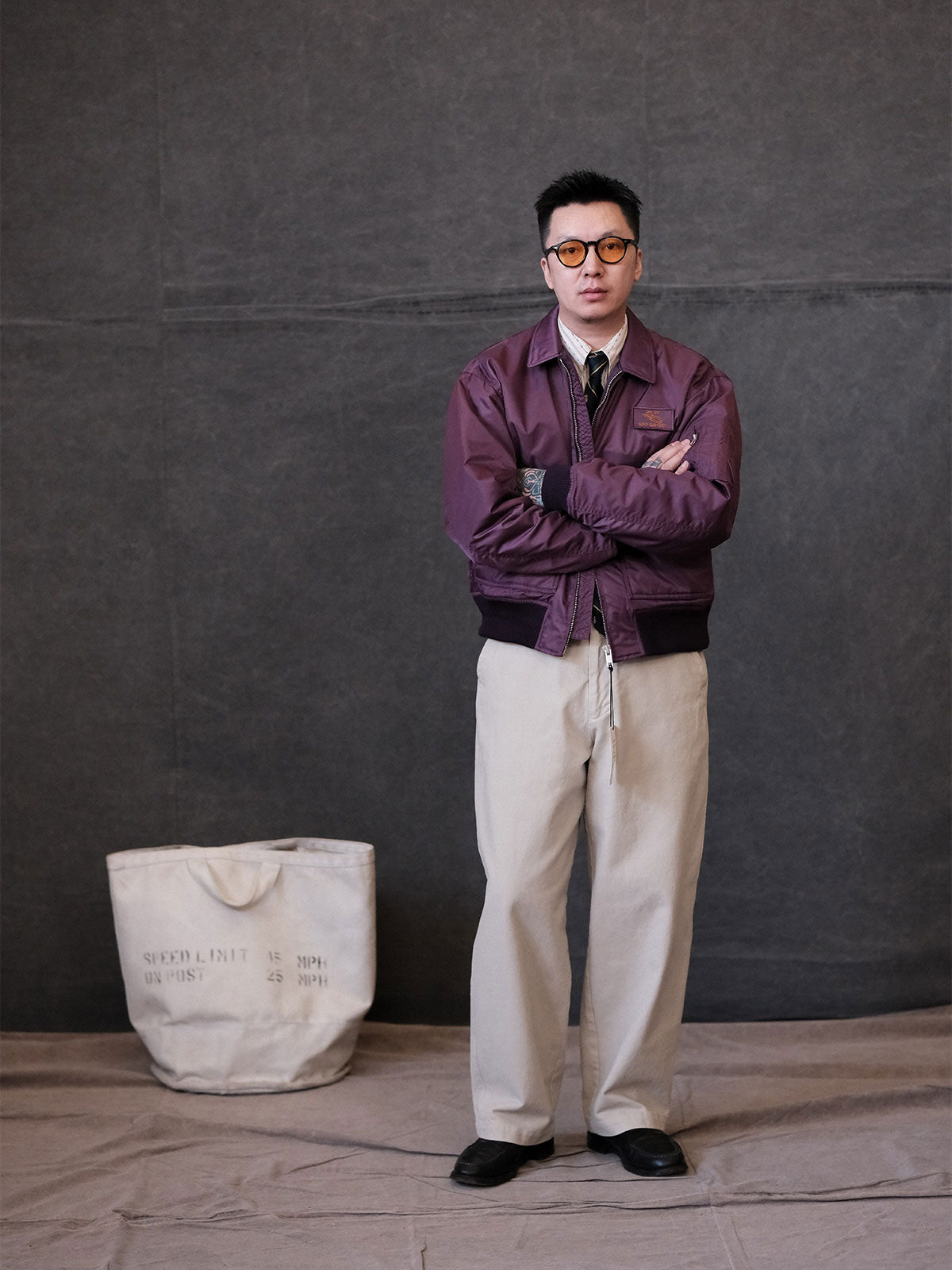 詳細画像:
TALONメタルジッパーとマジックテープエンブレムのディテール。フラップポケットやリブ編みの袖口、裾など、ミリタリーウェア特有のデザインが強調された画像。
モデル画像:
モデルがCWU-45Pフライトジャケットを着用し、ジーンズやカーゴパンツと組み合わせて、クラシックなミリタリースタイルを披露している画像。