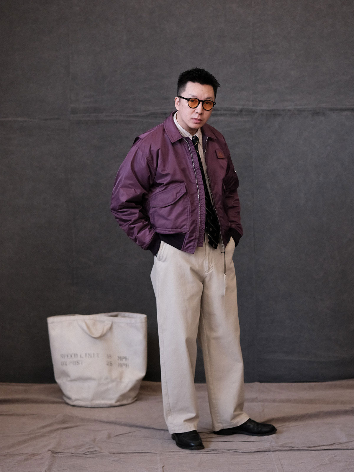 詳細画像:
TALONメタルジッパーとマジックテープエンブレムのディテール。フラップポケットやリブ編みの袖口、裾など、ミリタリーウェア特有のデザインが強調された画像。
モデル画像:
モデルがCWU-45Pフライトジャケットを着用し、ジーンズやカーゴパンツと組み合わせて、クラシックなミリタリースタイルを披露している画像。