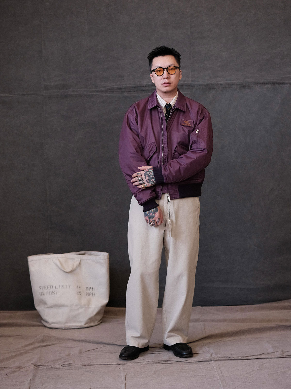 詳細画像:
TALONメタルジッパーとマジックテープエンブレムのディテール。フラップポケットやリブ編みの袖口、裾など、ミリタリーウェア特有のデザインが強調された画像。
モデル画像:
モデルがCWU-45Pフライトジャケットを着用し、ジーンズやカーゴパンツと組み合わせて、クラシックなミリタリースタイルを披露している画像。