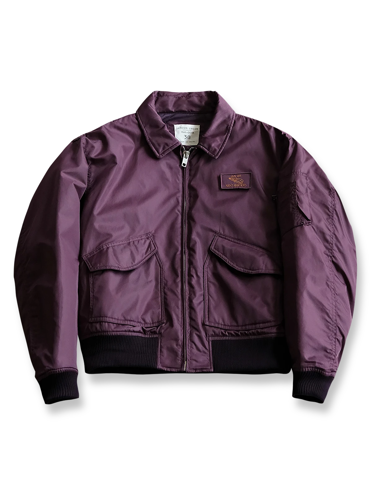 製品画像:
CWU-45Pフライトジャケットの全体展示。高密度ナイロン外層と厚手のキルティング綿を使用した、保温性と防風性に優れたクラシックなフライトジャケットの全体像。
詳細画像:
TALONメタルジッパーとマジックテープエンブレムのディテール。フラップポケットやリブ編みの袖口、裾など、ミリタリーウェア特有のデザインが強調された画像。