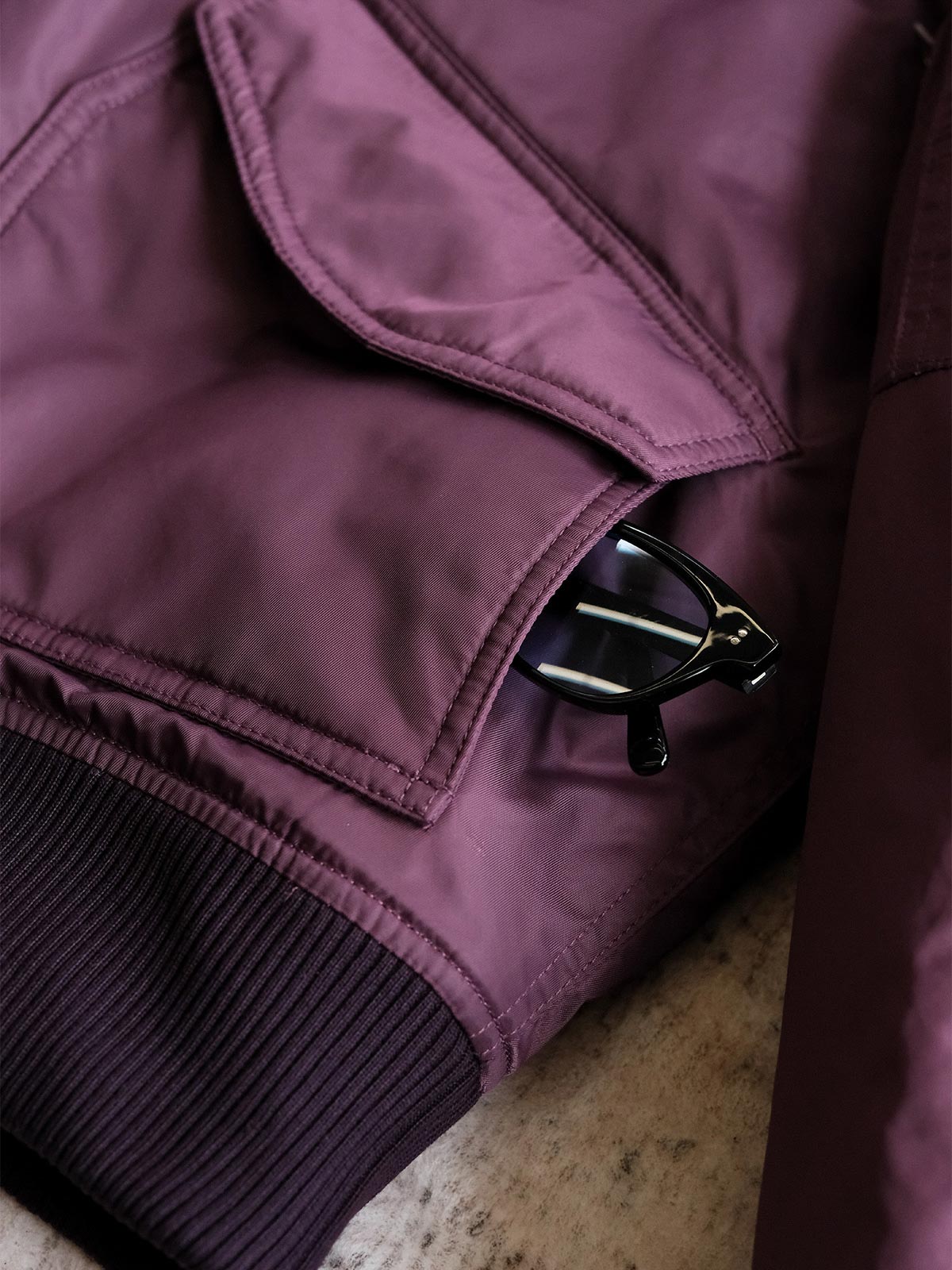 製品画像:
CWU-45Pフライトジャケットの全体展示。高密度ナイロン外層と厚手のキルティング綿を使用した、保温性と防風性に優れたクラシックなフライトジャケットの全体像。
詳細画像:
TALONメタルジッパーとマジックテープエンブレムのディテール。フラップポケットやリブ編みの袖口、裾など、ミリタリーウェア特有のデザインが強調された画像。