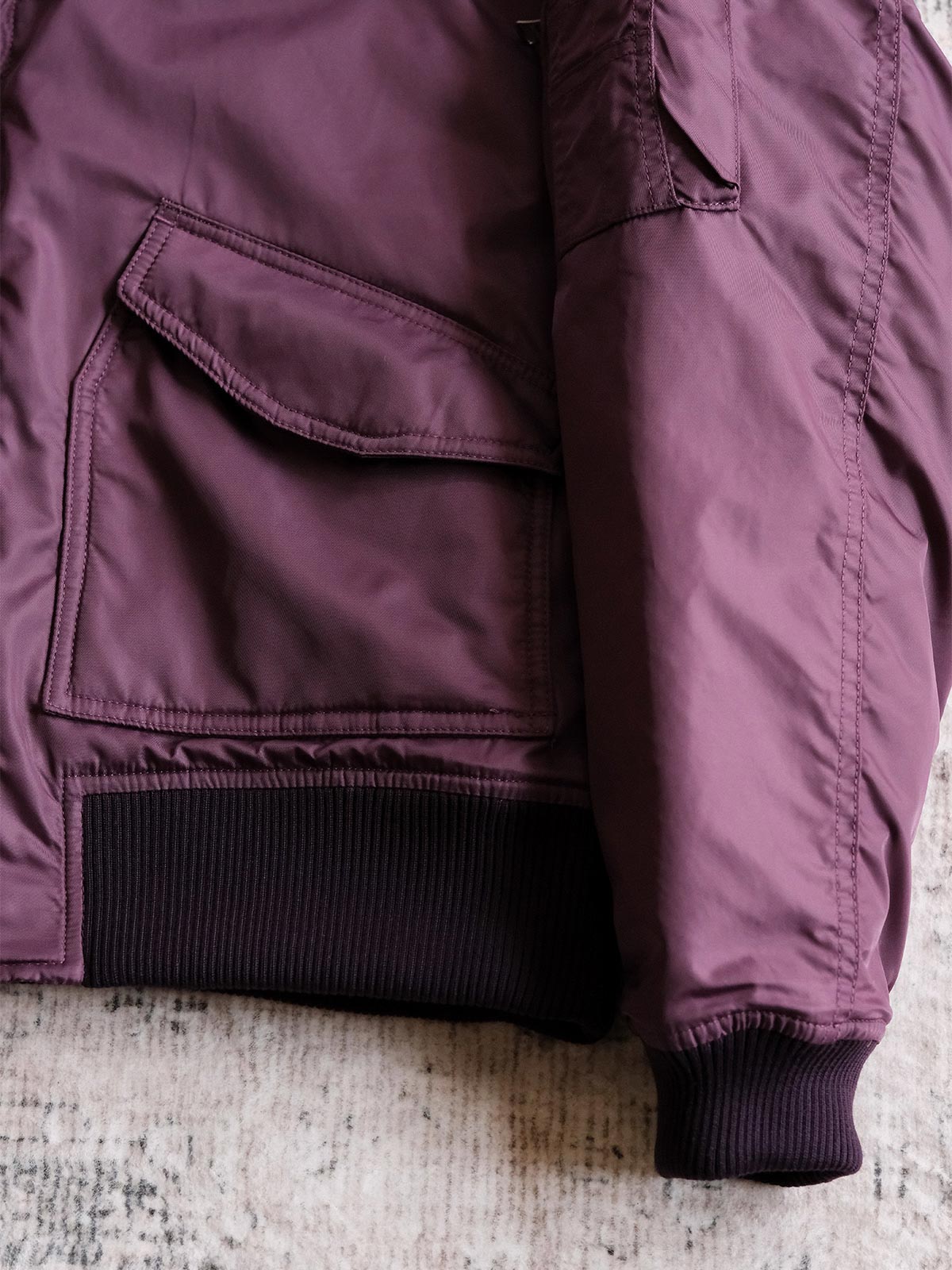 製品画像:
CWU-45Pフライトジャケットの全体展示。高密度ナイロン外層と厚手のキルティング綿を使用した、保温性と防風性に優れたクラシックなフライトジャケットの全体像。
詳細画像:
TALONメタルジッパーとマジックテープエンブレムのディテール。フラップポケットやリブ編みの袖口、裾など、ミリタリーウェア特有のデザインが強調された画像。