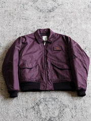 製品画像:
CWU-45Pフライトジャケットの全体展示。高密度ナイロン外層と厚手のキルティング綿を使用した、保温性と防風性に優れたクラシックなフライトジャケットの全体像。
詳細画像:
TALONメタルジッパーとマジックテープエンブレムのディテール。フラップポケットやリブ編みの袖口、裾など、ミリタリーウェア特有のデザインが強調された画像。