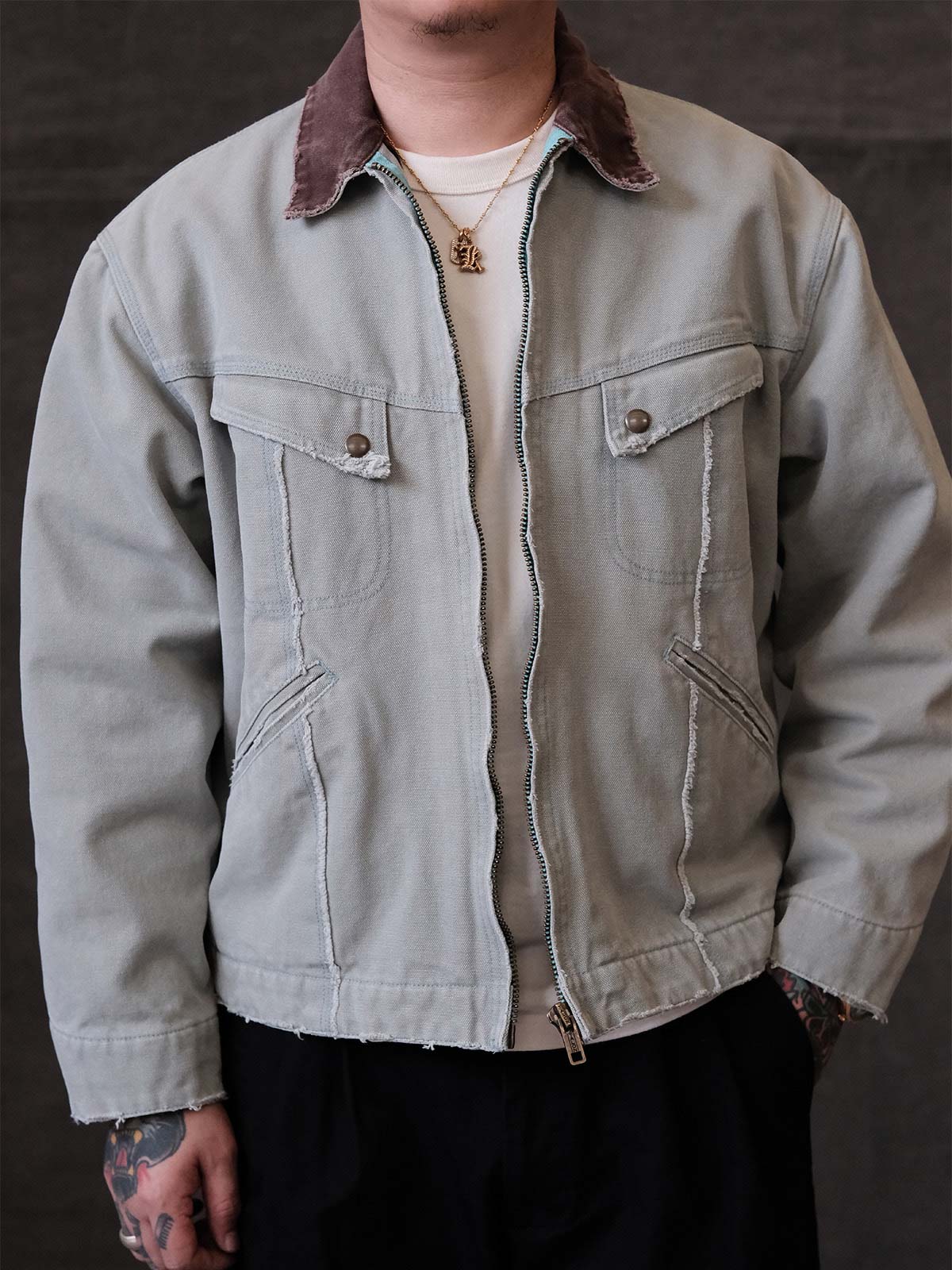 詳細画像:
TALONジッパー、スナップボタン、及び水洗い加工のディテール。多重水洗い加工と手作業のダメージ加工が施された、ヴィンテージ感が強調されたディテール。
モデル画像:
モデルがリバイバルキャンバスジャケットを着用し、カーゴパンツと合わせてアメリカンリバイバルスタイルを演出している画像。