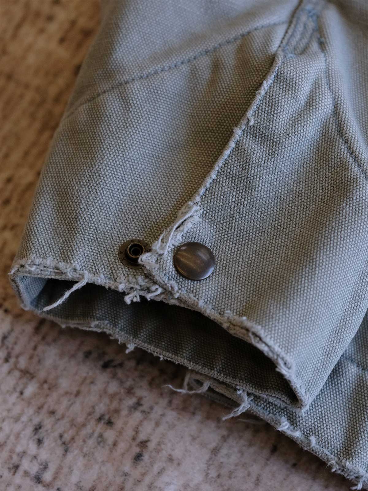 製品画像:
リバイバルダメージパッチワークキャンバスジャケット全体展示。15ozの定織キャンバスと日本製厚ウール裏地を使用し、ヴィンテージスタイルを引き立てるタフなキャンバスジャケットの全体像。
詳細画像:
TALONジッパー、スナップボタン、及び水洗い加工のディテール。多重水洗い加工と手作業のダメージ加工が施された、ヴィンテージ感が強調されたディテール。