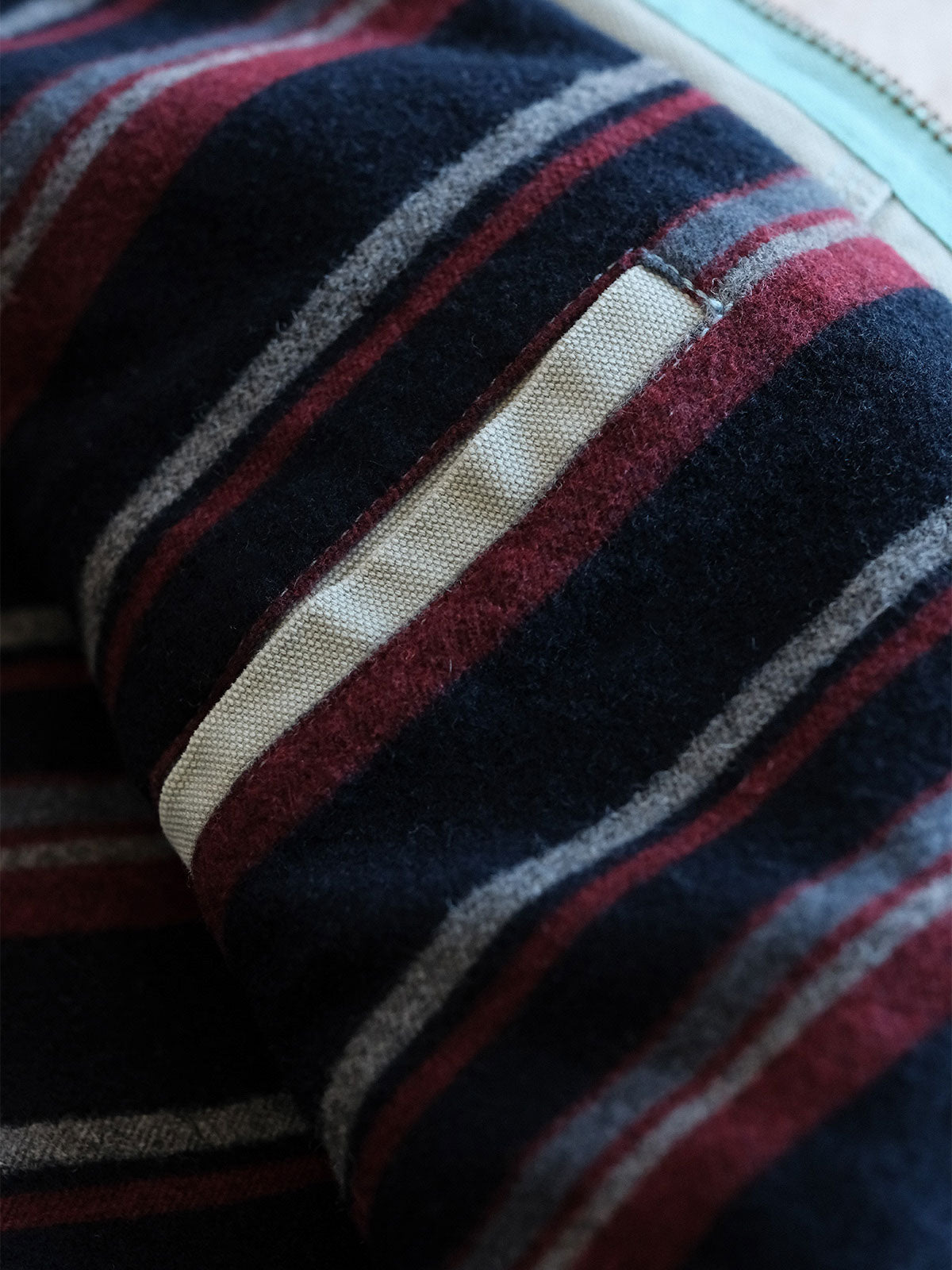 製品画像:
リバイバルダメージパッチワークキャンバスジャケット全体展示。15ozの定織キャンバスと日本製厚ウール裏地を使用し、ヴィンテージスタイルを引き立てるタフなキャンバスジャケットの全体像。
詳細画像:
TALONジッパー、スナップボタン、及び水洗い加工のディテール。多重水洗い加工と手作業のダメージ加工が施された、ヴィンテージ感が強調されたディテール。