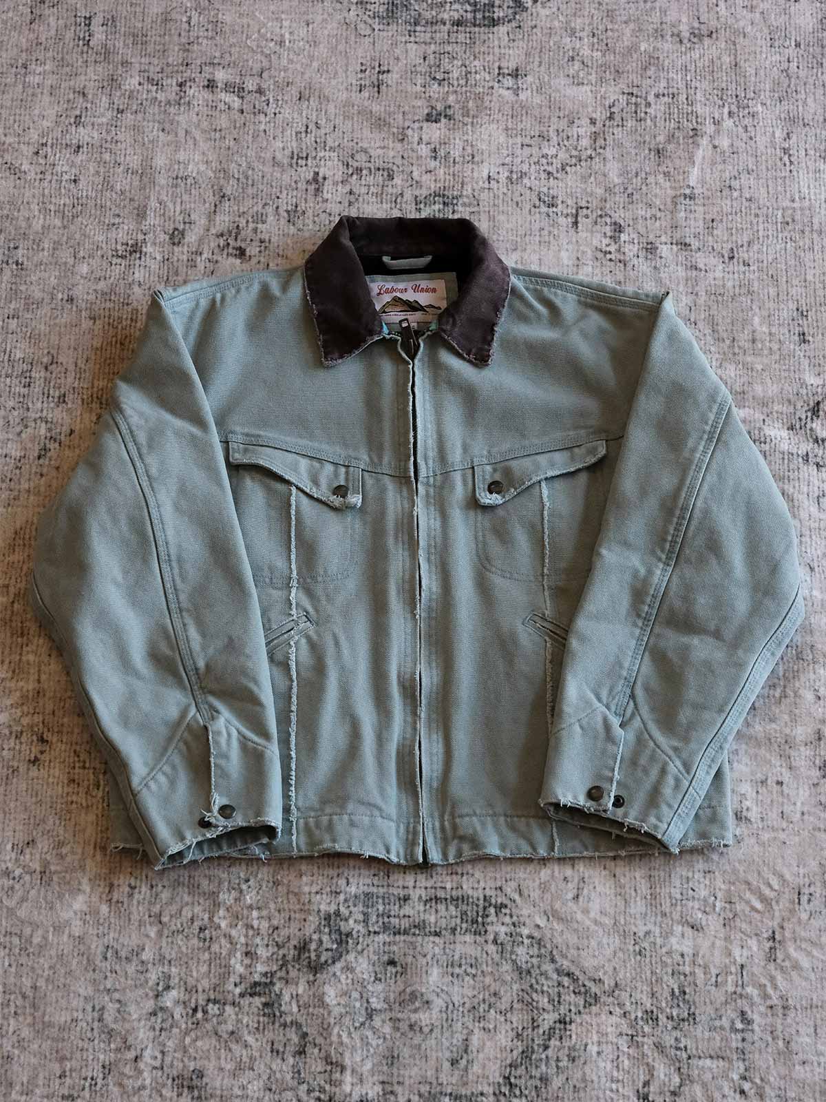 製品画像:
リバイバルダメージパッチワークキャンバスジャケット全体展示。15ozの定織キャンバスと日本製厚ウール裏地を使用し、ヴィンテージスタイルを引き立てるタフなキャンバスジャケットの全体像。
詳細画像:
TALONジッパー、スナップボタン、及び水洗い加工のディテール。多重水洗い加工と手作業のダメージ加工が施された、ヴィンテージ感が強調されたディテール。