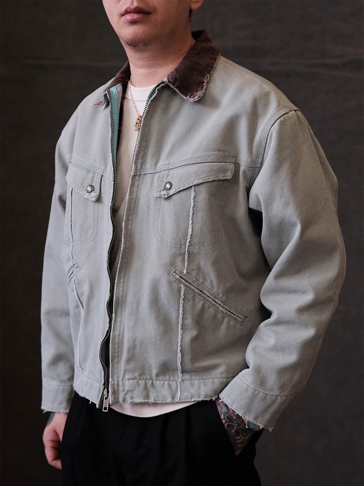 詳細画像:
TALONジッパー、スナップボタン、及び水洗い加工のディテール。多重水洗い加工と手作業のダメージ加工が施された、ヴィンテージ感が強調されたディテール。
モデル画像:
モデルがリバイバルキャンバスジャケットを着用し、カーゴパンツと合わせてアメリカンリバイバルスタイルを演出している画像。