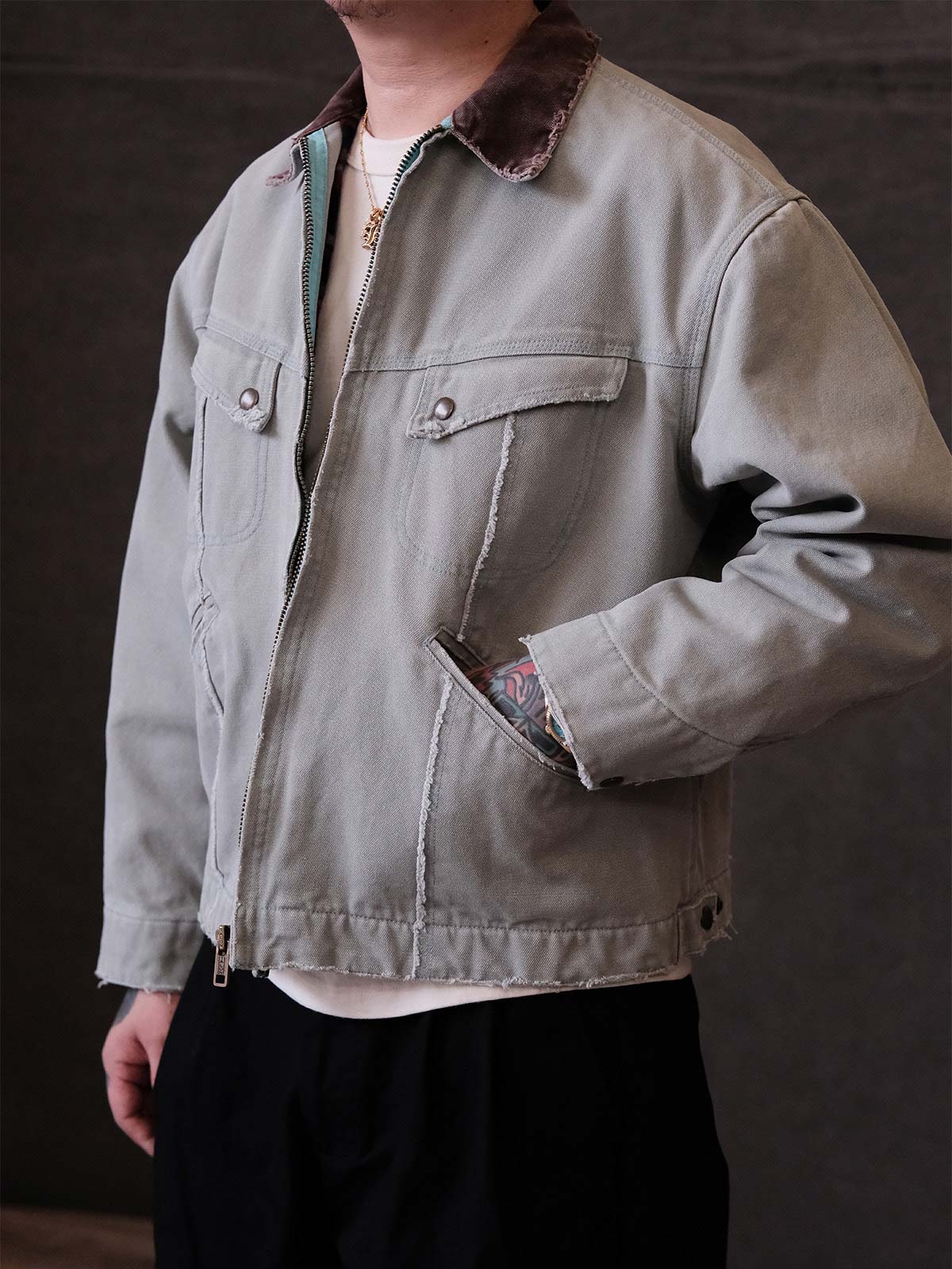 詳細画像:
TALONジッパー、スナップボタン、及び水洗い加工のディテール。多重水洗い加工と手作業のダメージ加工が施された、ヴィンテージ感が強調されたディテール。
モデル画像:
モデルがリバイバルキャンバスジャケットを着用し、カーゴパンツと合わせてアメリカンリバイバルスタイルを演出している画像。