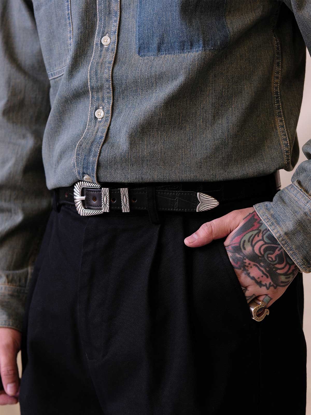 
詳細画像:
エッチング加工された真鍮バックルのディテール。精緻な彫刻が施された立体感のあるバックルが、ヴィンテージスタイルの魅力を引き立てるディテール。
モデル画像:
モデルがヴィンテージキャバルリーベルトを着用し、デニムやカーゴパンツと合わせて、アメリカンウェスタンスタイルを披露している画像。