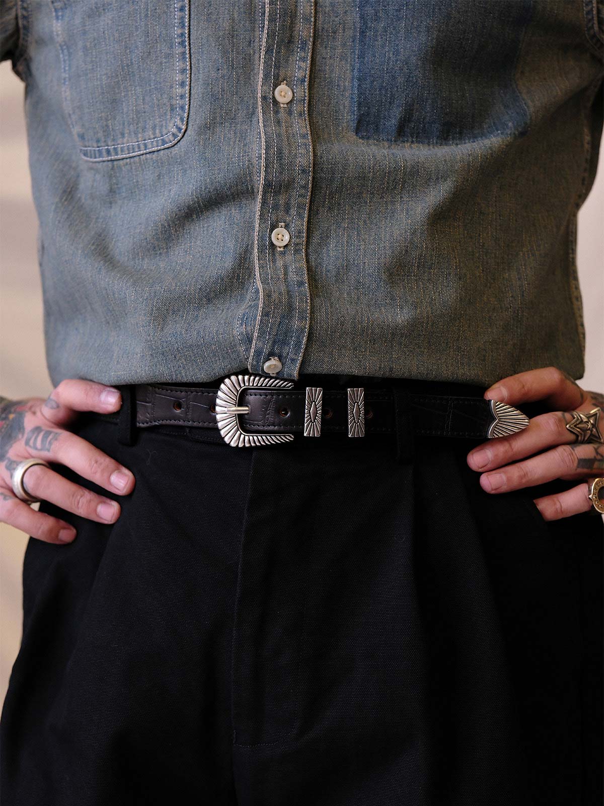 詳細画像:
エッチング加工された真鍮バックルのディテール。精緻な彫刻が施された立体感のあるバックルが、ヴィンテージスタイルの魅力を引き立てるディテール。
モデル画像:
モデルがヴィンテージキャバルリーベルトを着用し、デニムやカーゴパンツと合わせて、アメリカンウェスタンスタイルを披露している画像。