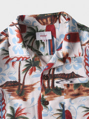 トロピカルプリント半袖シャツのディテールクローズアップ。精密なプリントとフロントポケットのデザインが特徴で、夏の装いに洗練されたタッチを加えます。
