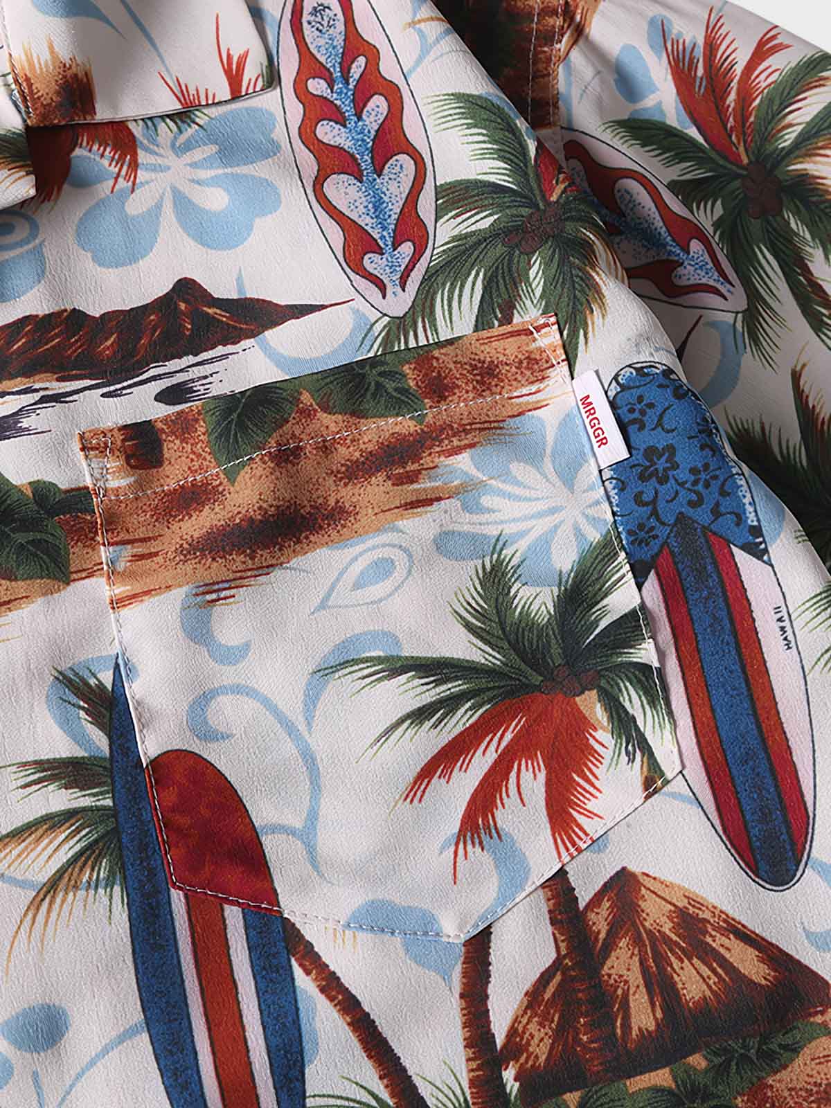 トロピカルプリント半袖シャツのディテールクローズアップ。精密なプリントとフロントポケットのデザインが特徴で、夏の装いに洗練されたタッチを加えます。