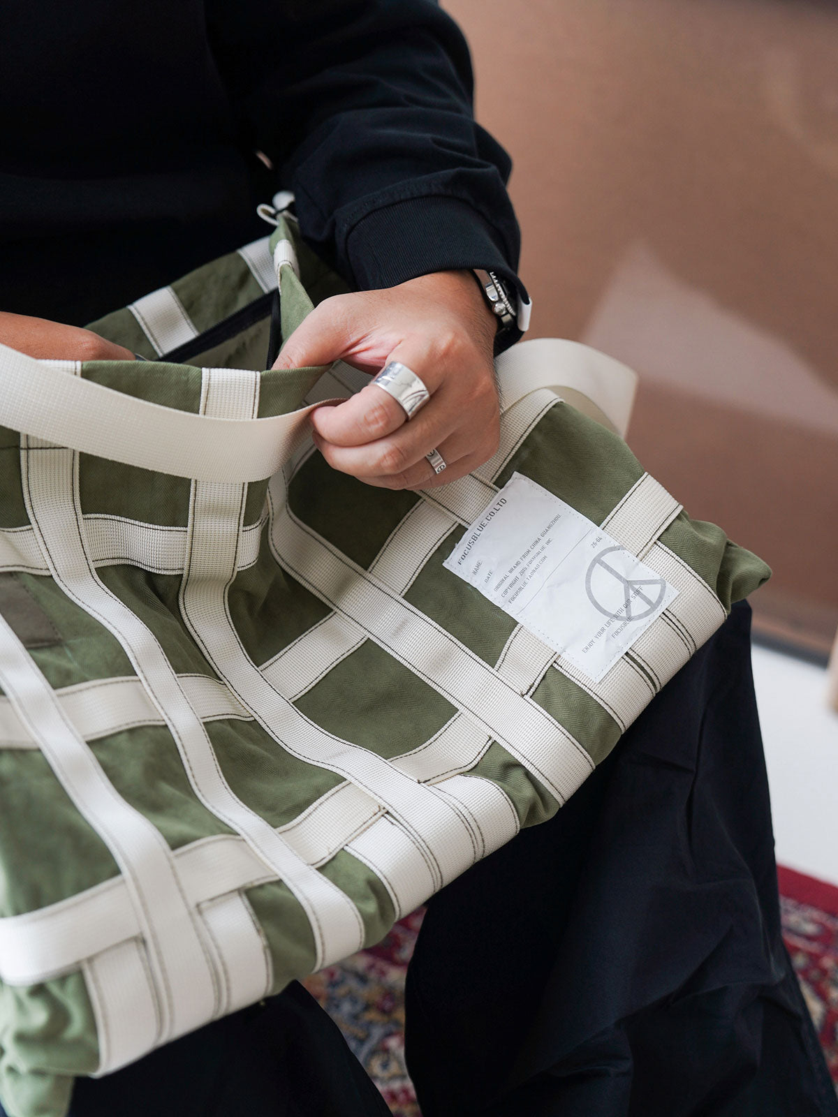 製品画像: ミリタリーテイストのショルダーバッグの全体展示
詳細画像: テントファブリックとウェビングのディテール
モデル画像: モデルが着用したミリタリーショルダーバッグのスタイリング例