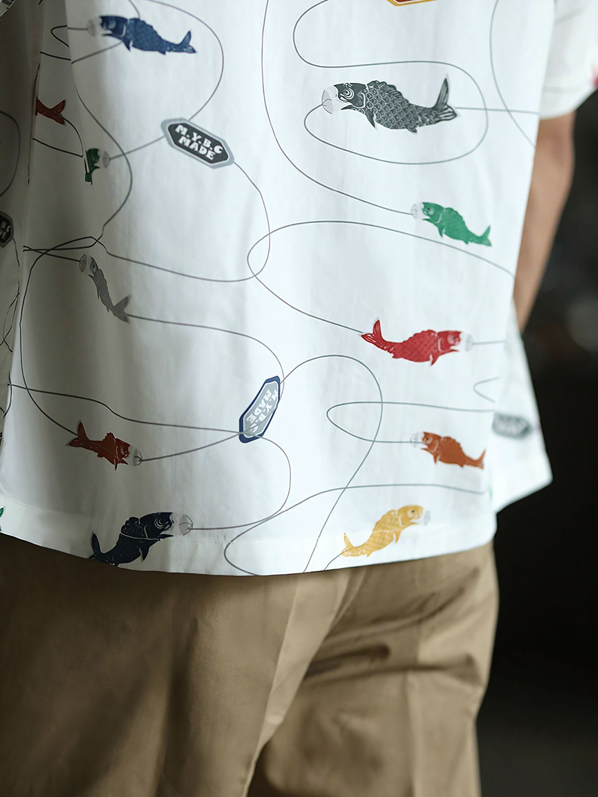 モデルが鯉プリントのハワイアンシャツを着用し、夏のカジュアルスタイルを披露。