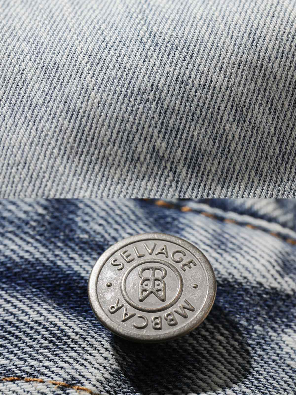 ジーンズの膝部分の手作業によるダメージ加工とレールトラックウォッシュの細部を示すクローズアップ。