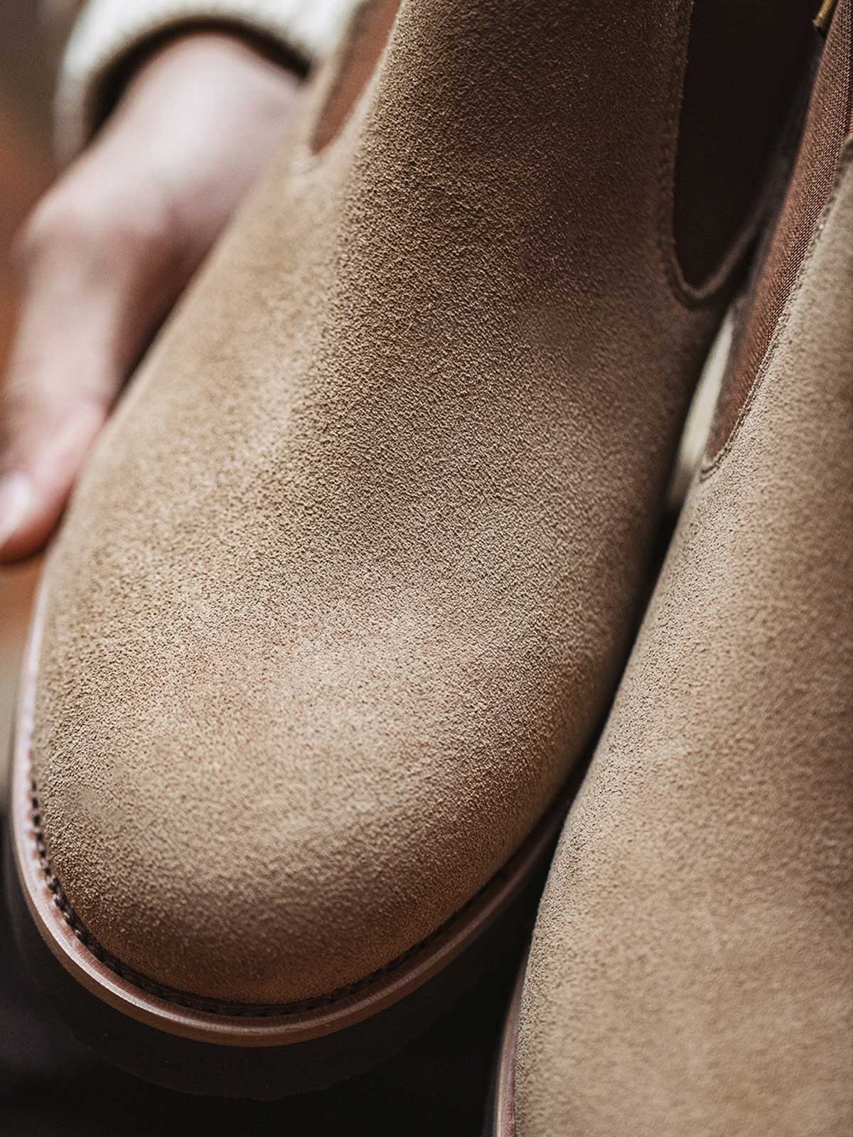 製品画像:
ライトブラウンのスエードチェルシーブーツ全体画像。シンプルで洗練されたデザインが特徴で、秋冬シーズンに最適なスタイルを提案します。

詳細画像:
チェルシーブーツのゴムバンドとスエードの質感がクローズアップされたディテール画像。履きやすさとデザインの美しさが強調されています。