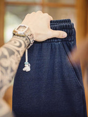 製品画像: ワッフルニットドレープ効果付きカジュアルパンツ正面図
詳細画像: パンツのディテール、白い編み込みドローストリングと石風ビーズ