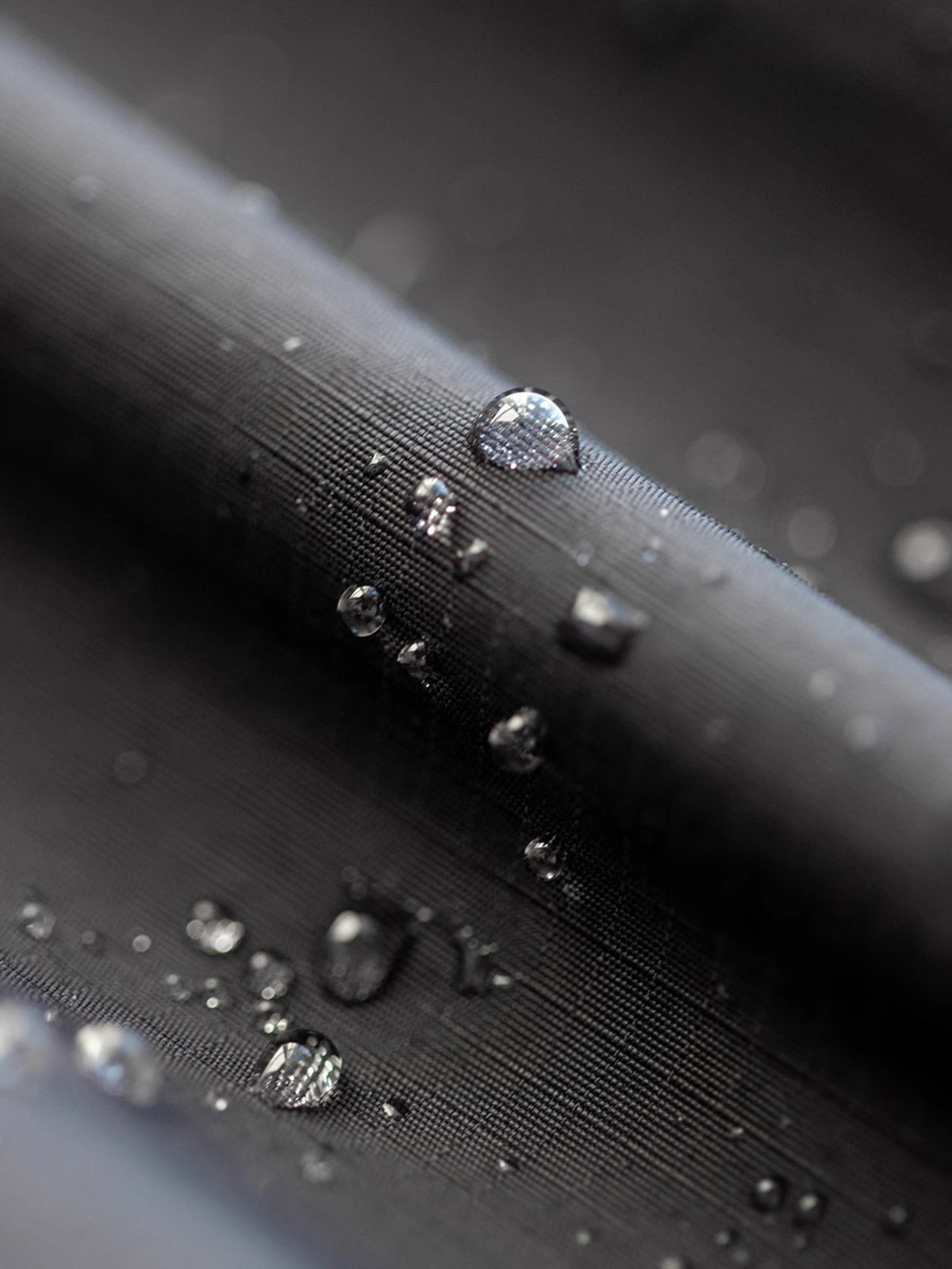 製品画像: 三つポケット撥水性フード付きテクニカルジャケット 正面、アウトドアから都市通勤まで対応
詳細画像: グロメットジッパーとレインシェルデザインのディテール、防護性能