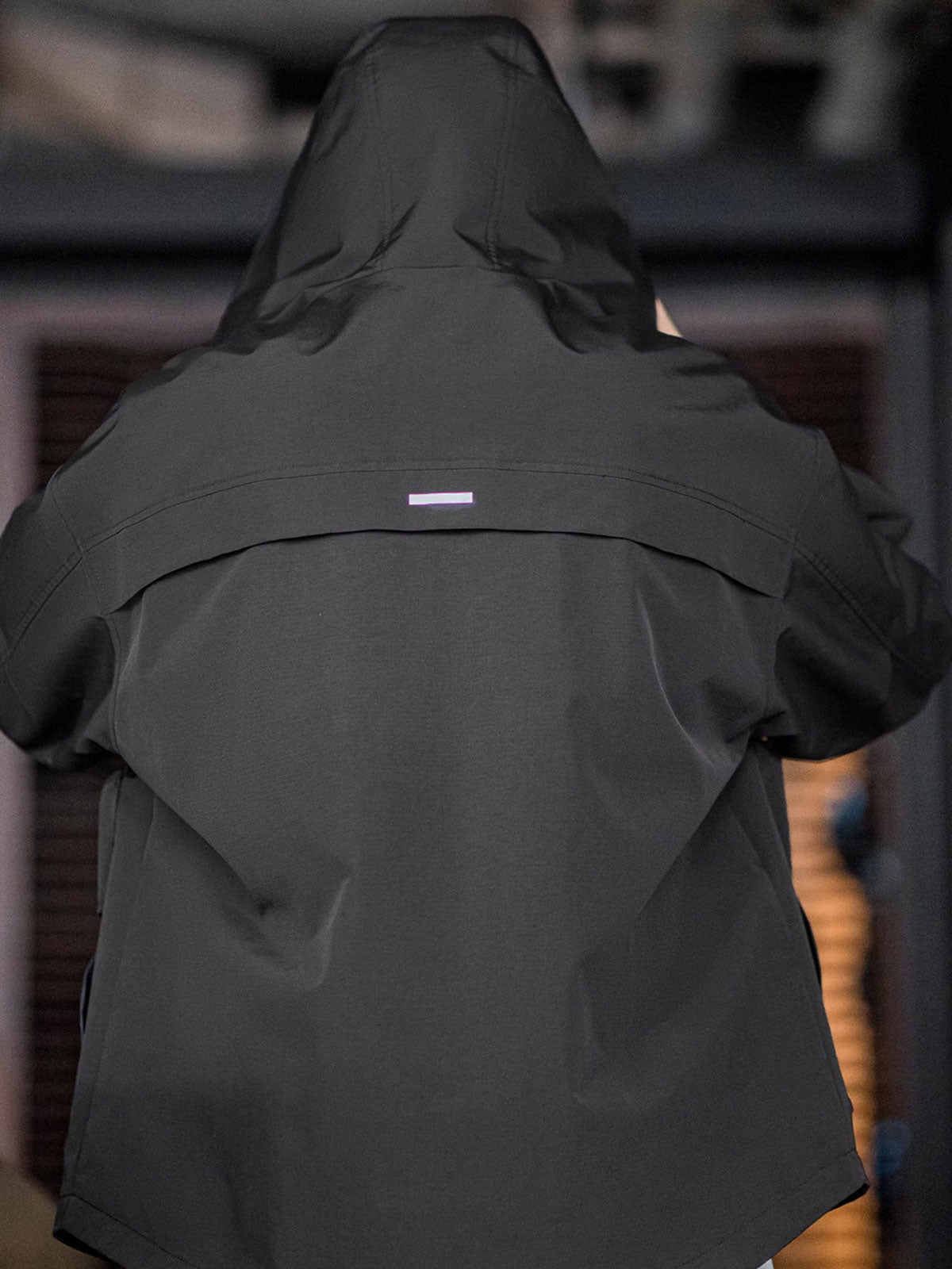 製品画像: 三つポケット撥水性フード付きテクニカルジャケット 正面、アウトドアから都市通勤まで対応
詳細画像: グロメットジッパーとレインシェルデザインのディテール、防護性能