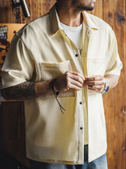 モデルがノンアイロン竹節平織オーバーサイズ半袖シャツを着用し、カジュアルパンツとシンプルなスニーカーでコーディネート。リラックスした夏のスタイルを演出し、アクセサリーでスタイリッシュなアクセントを加えています。